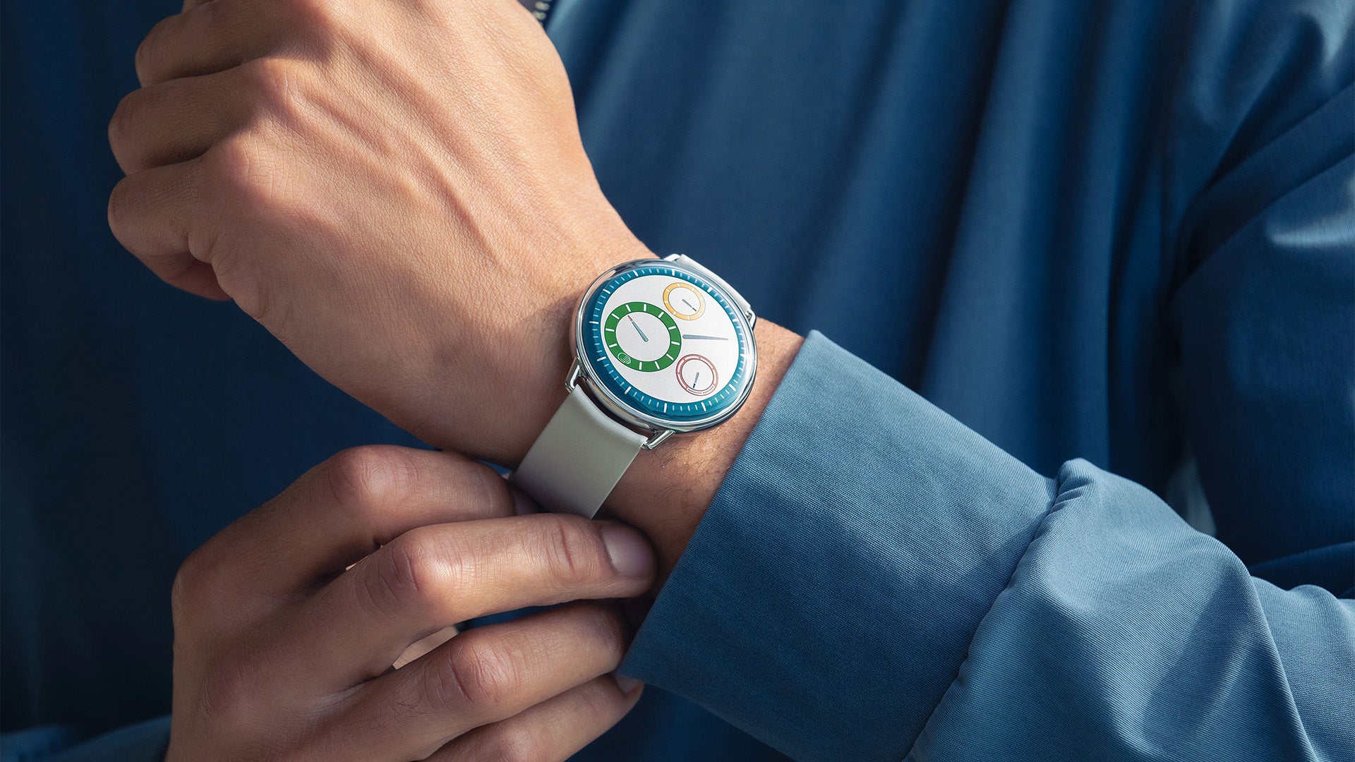 Ressence TYPE 1° Round Multicolour on a person's wrist with a white rubber strap against a dark background