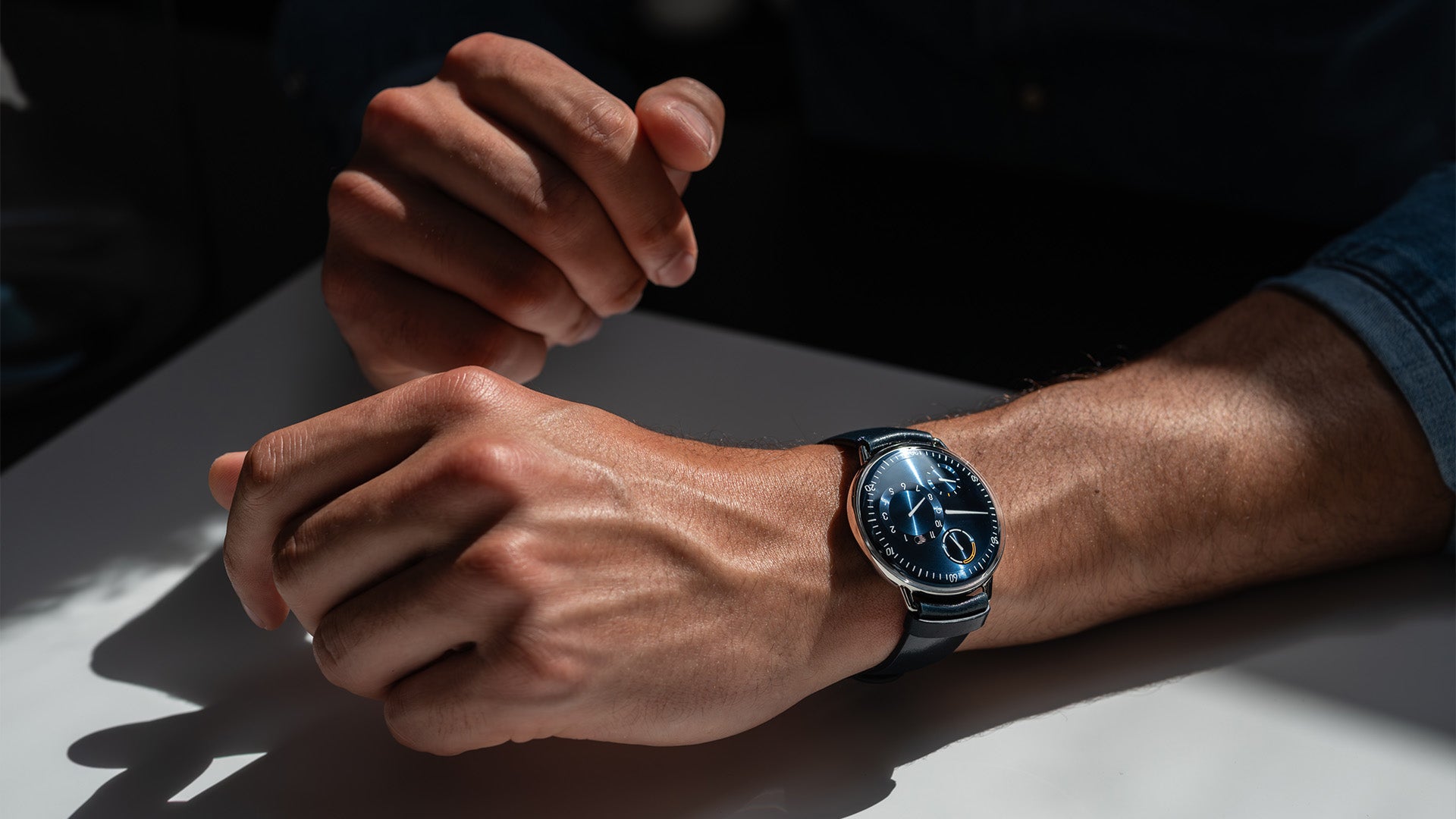 Ressence TYPE 1 Round Night Blue, the essential titanium watch, shown dial-up on a man's wrist