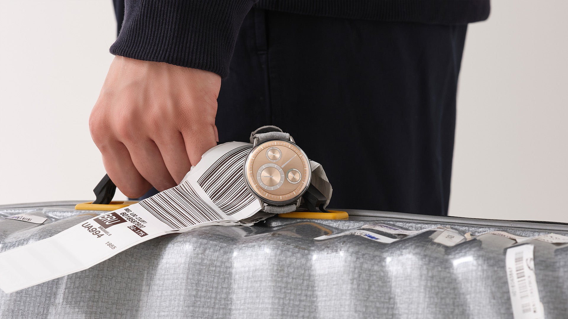 Ressence TYPE 1° Round Rose Gold watch attached to a luggage with a tag showing Brussels as the destination