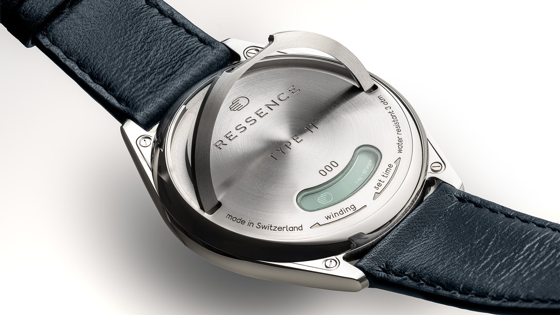 Close-up of a Ressence TYPE 11 watch's caseback with the lever replacing the crown of the watch lifted up, with a blue strap on a white background