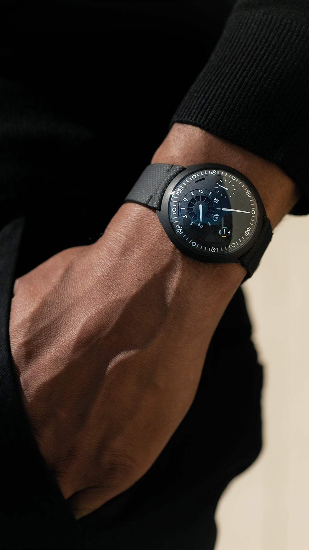 Vertical image of a person wearing a Ressence TYPE 1 Anthracite innovative dual time-zone watch with their hand in the pocket me-zone