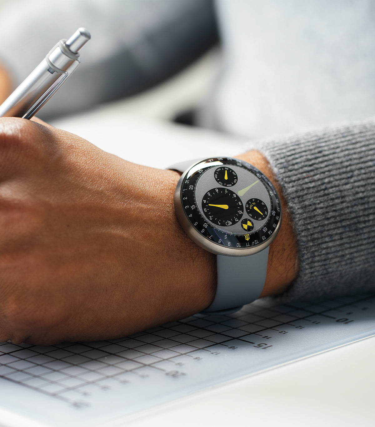 Vertical image of a person wearing the limited edition oil-filled Ressence TYPE 3 Marc Newson while writing on paper. The TYPE 3 is Ressence’s iconic watch, winner of multiple competitions such as the GPHG and the Red Dot Best of the Best award.