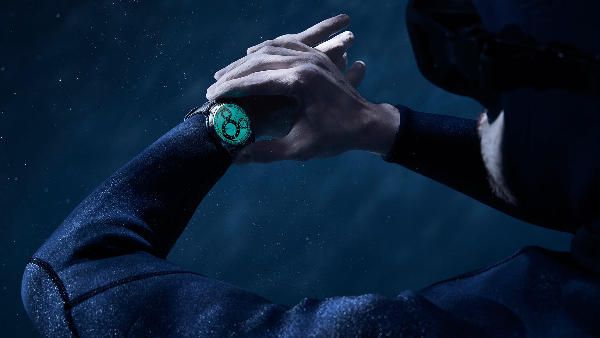 A diver looking at his Ressence TYPE 5 Luminova, the ultimate titanium divers' watch, legible under every angle and any light conditions thanks to its oil-filled dial entirely filled with Super Luminova