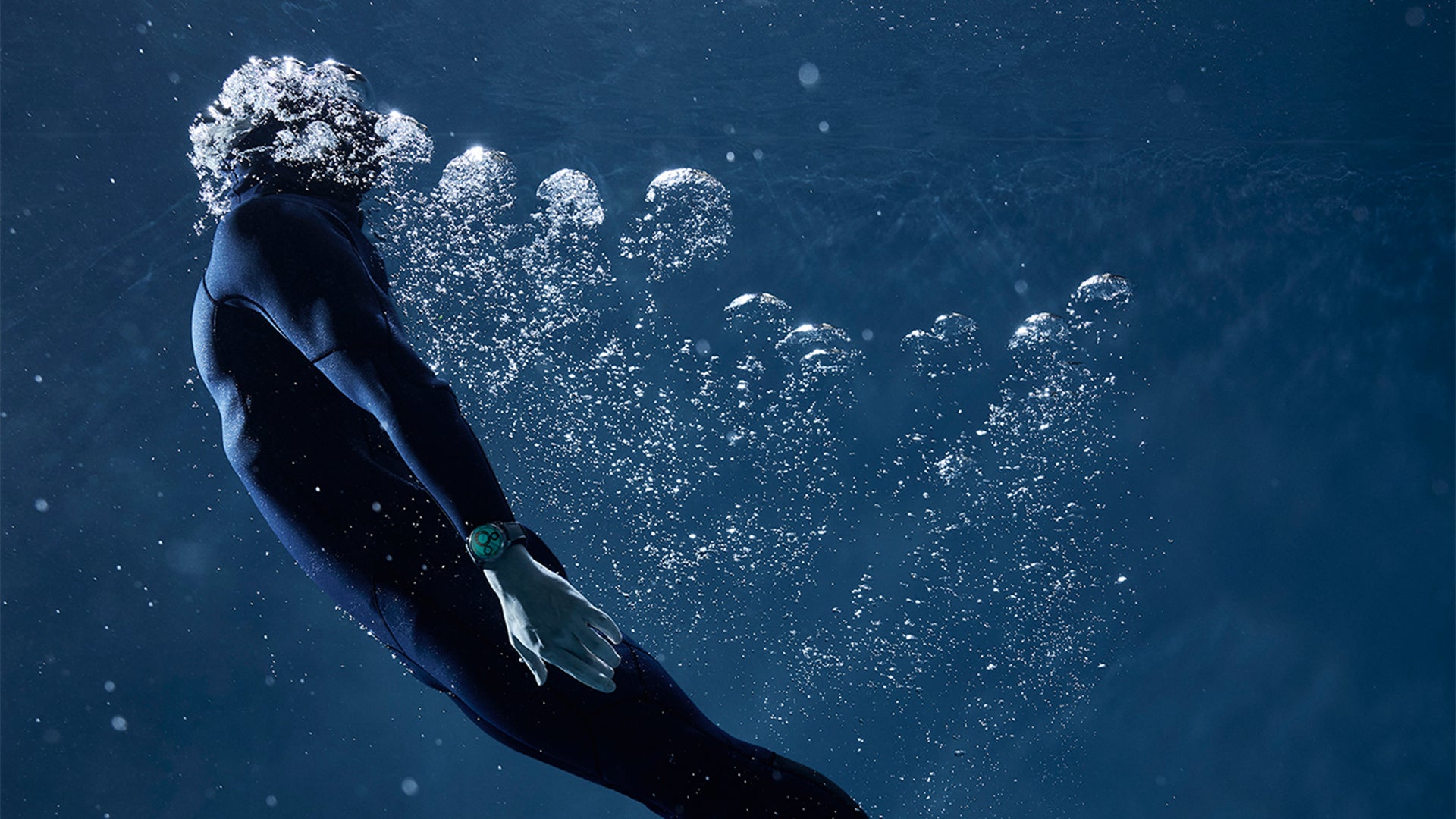A diver going back to the surface, surrounded by air bubbles and wearing the Ressence TYPE 5 Luminova, an oil-filled diver watch with its dial fully filled with Super Luminova