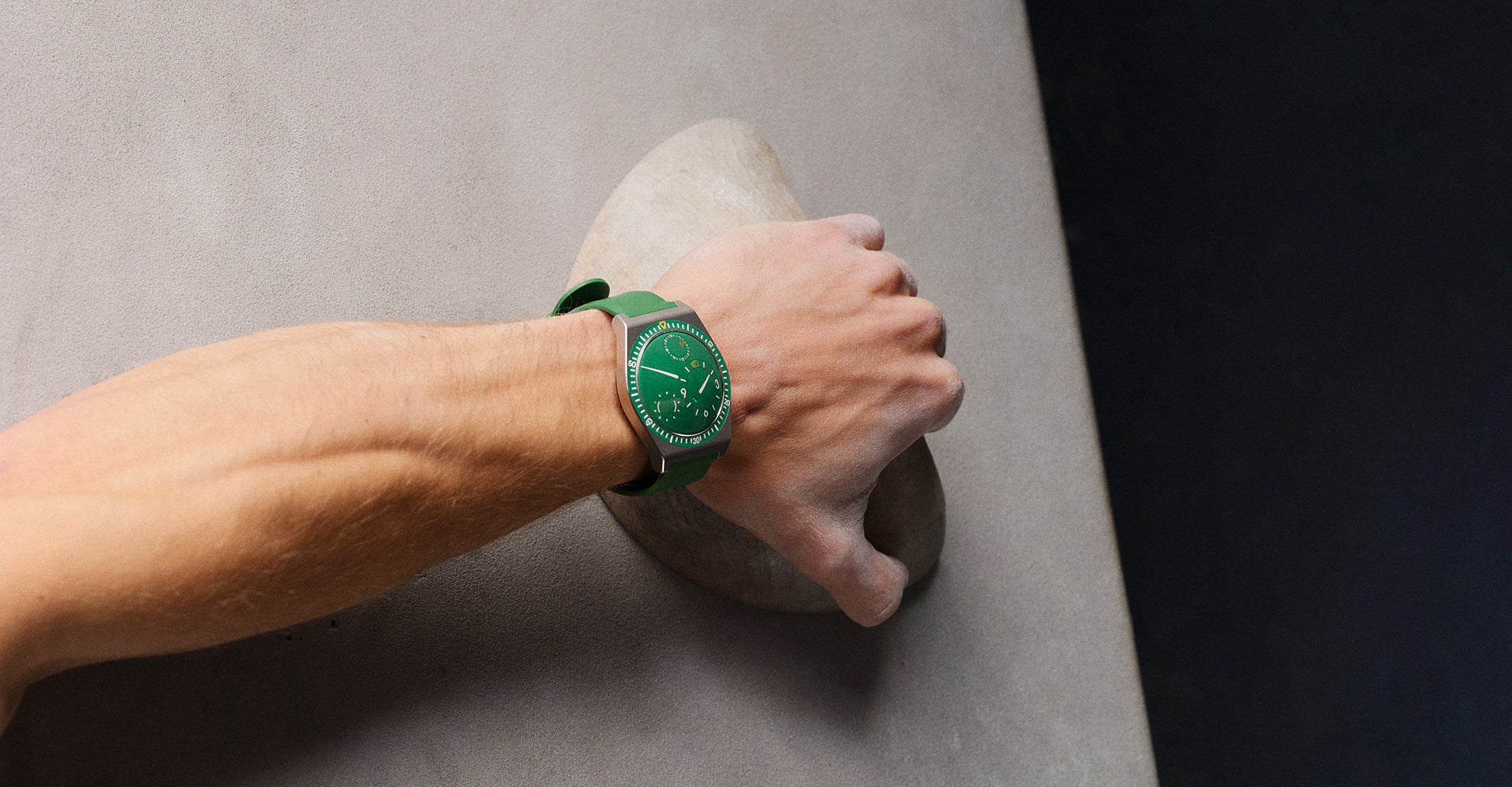 Ressence TYPE 7 Cactus, a titanium GMT watch with a green dial, shown as worn by a person bouldering on a wall