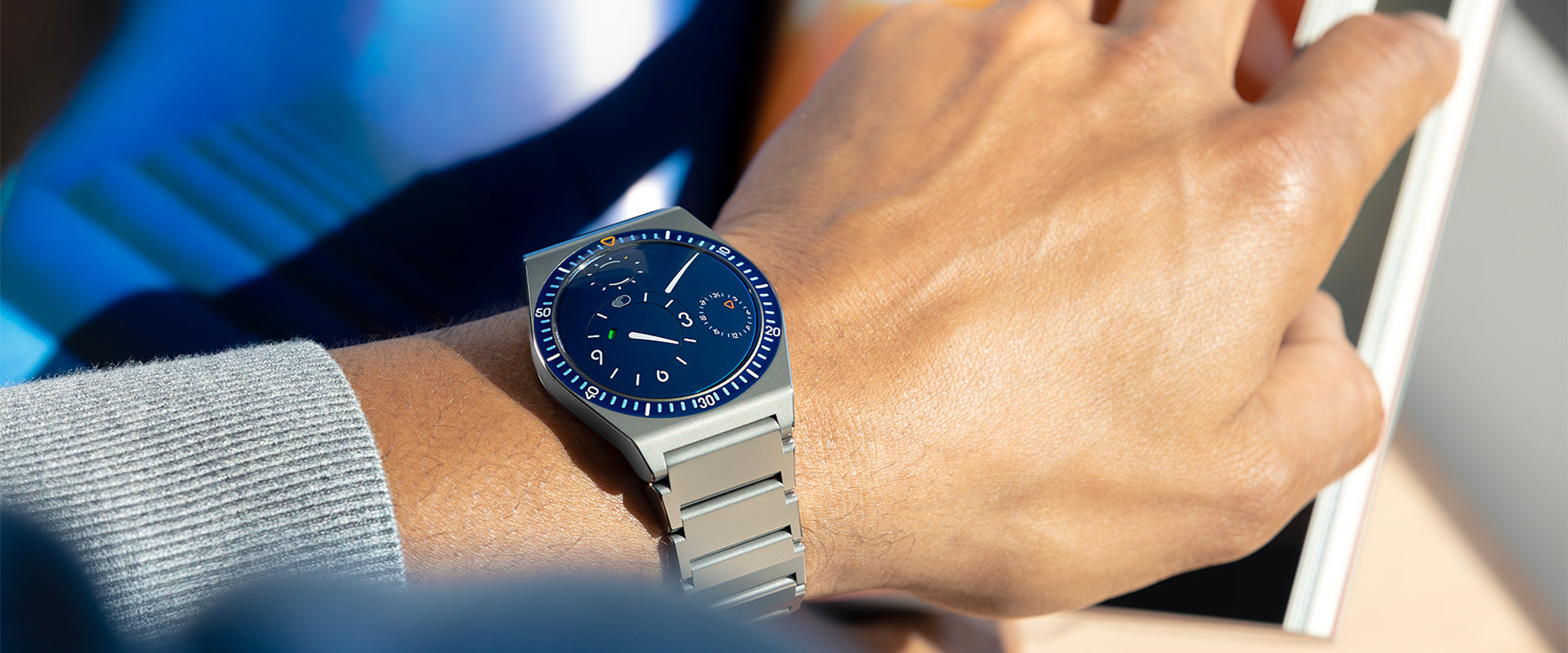 Close-up of a person's wrist wearing a night blue Ressence TYPE 7 sport-chic GMT watch with a titanium integrated bracelet.